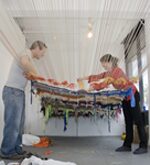 Two people holding colorful fabric artwork